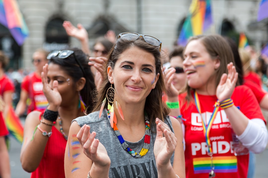 A joyful crowd of people waving rainbow flags during Pride in London along the parade route