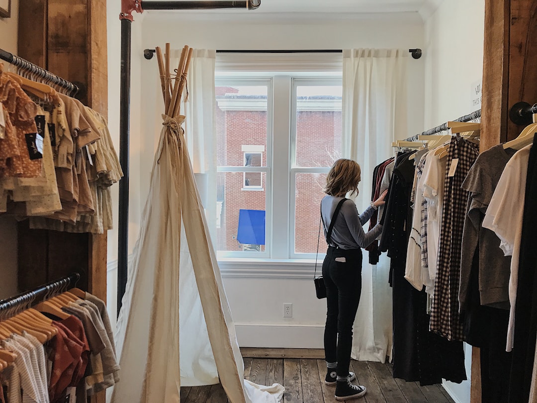 A woman carefully browsing a curated rail of slow fashion garments inside a small London boutique
