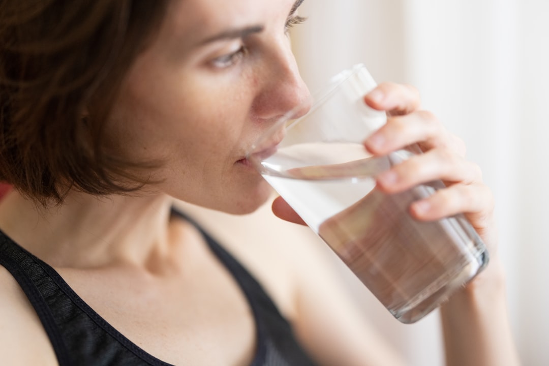 A woman starting her morning routine with a glass of water before the London heat builds outside her window