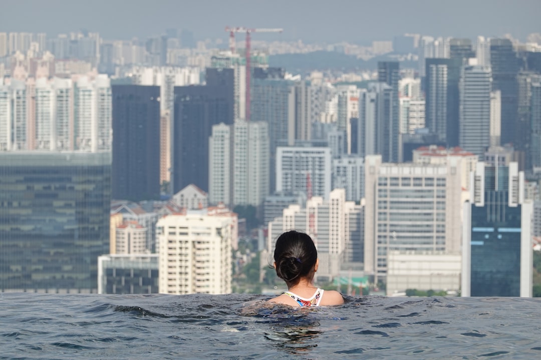 A woman swimming in one of London's rooftop pools with the city skyline visible through floor-to-ceiling windows