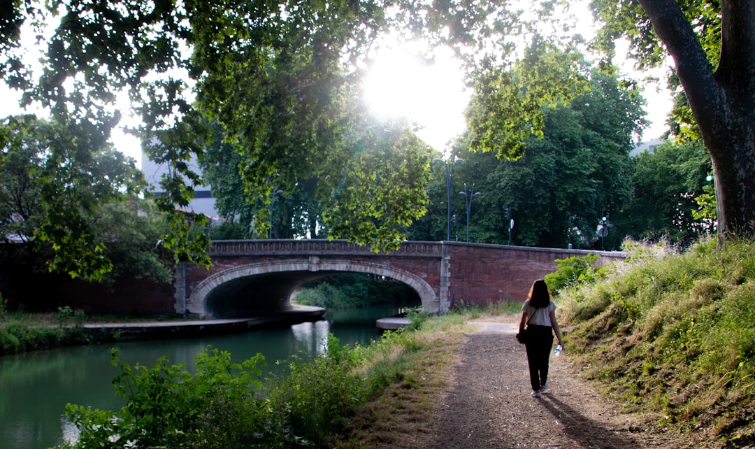A woman walks along London's canal towpaths on a sunny summer morning with narrowboats moored behind her