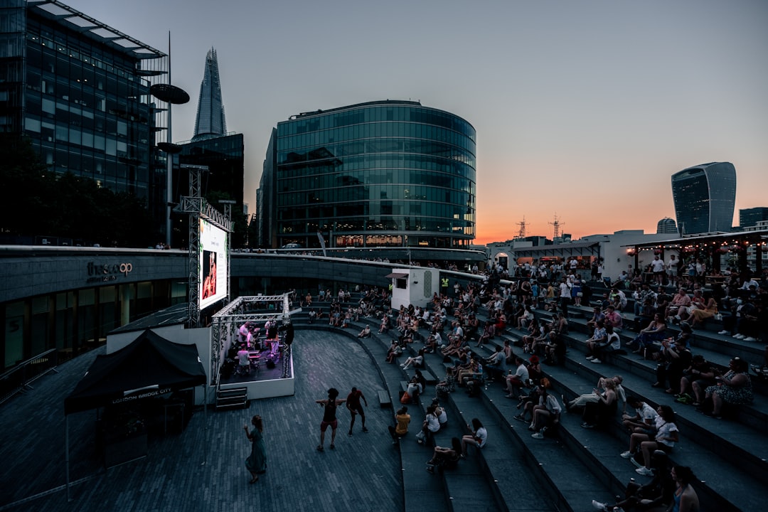 A crowd of people watching a free outdoor theatre performance in a London park during summer