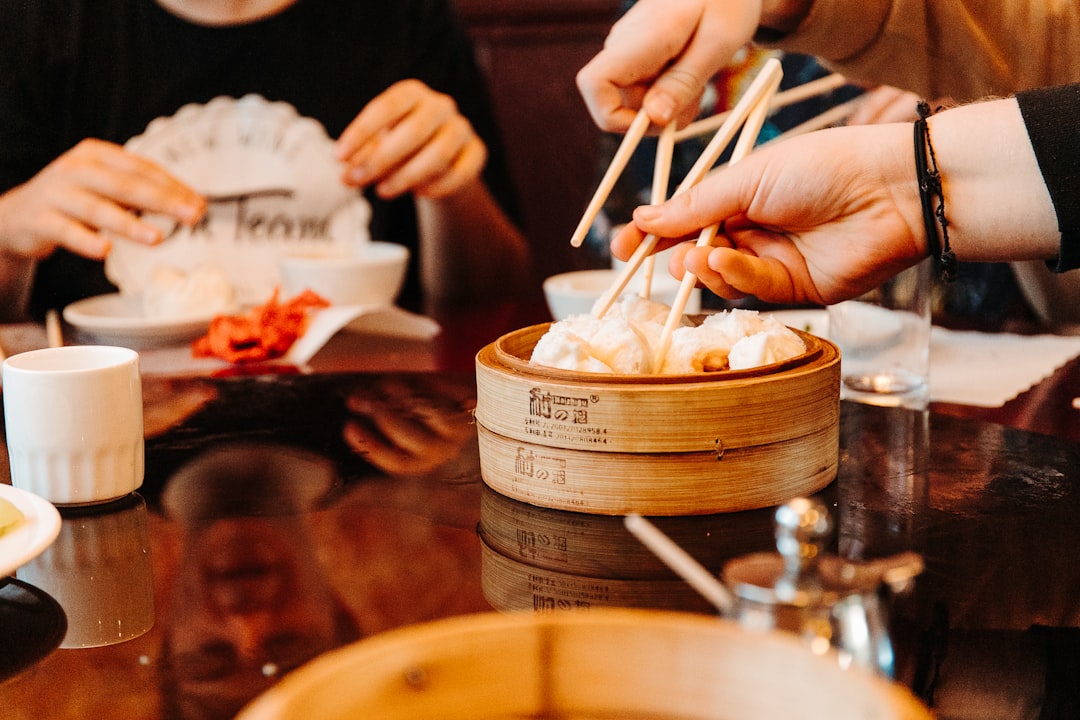 A woman smiling while sharing dim sum dishes with friends at a London Cantonese restaurant