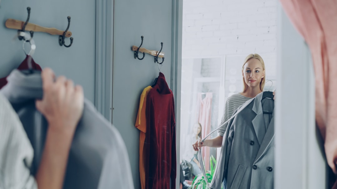 A woman reviewing her London wardrobe items on a bed, preparing for a seasonal transition from summer to autumn