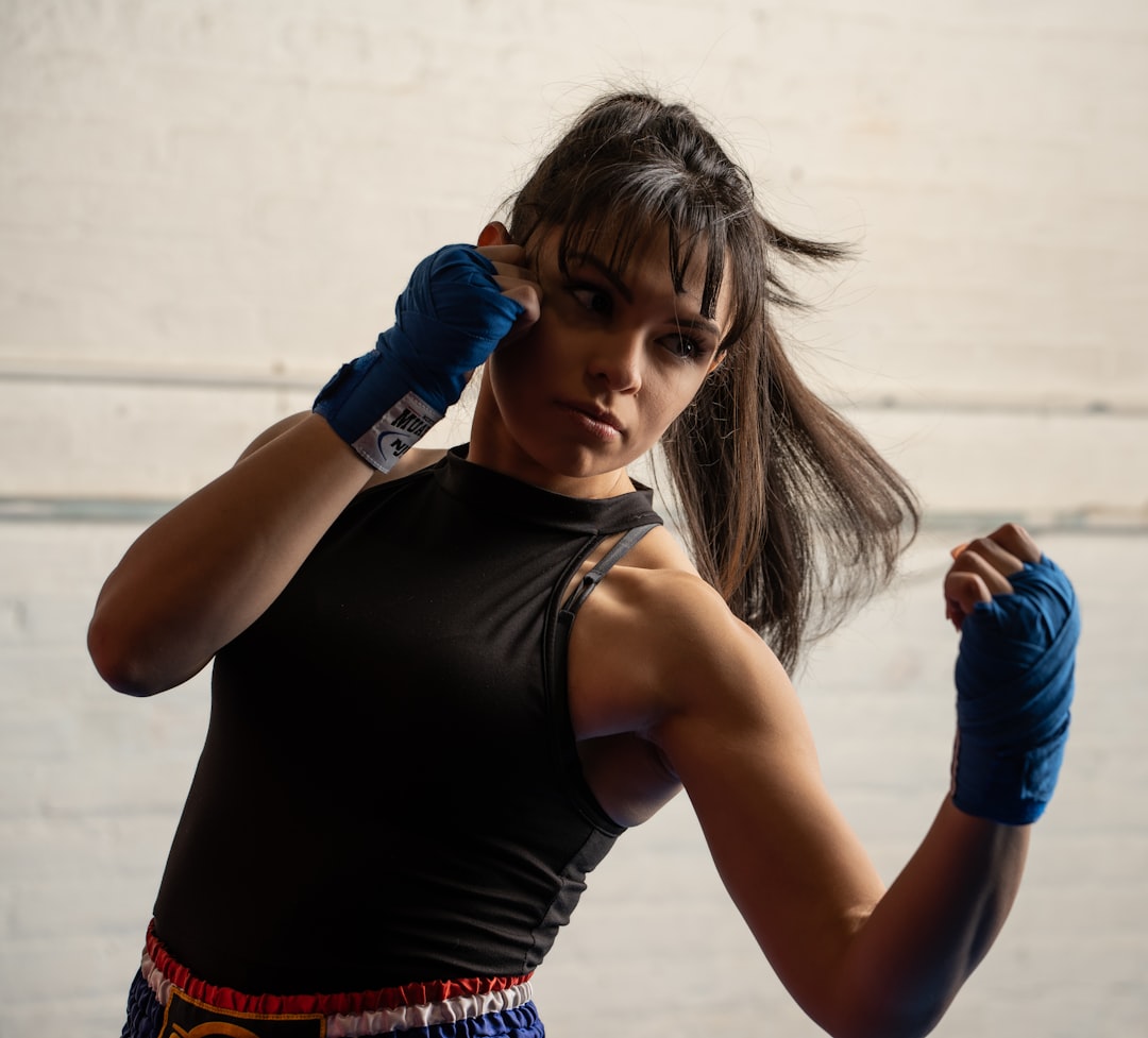 A woman wrapping her hands before her first session at a boxing gym in London, preparing to train with a coach nearby