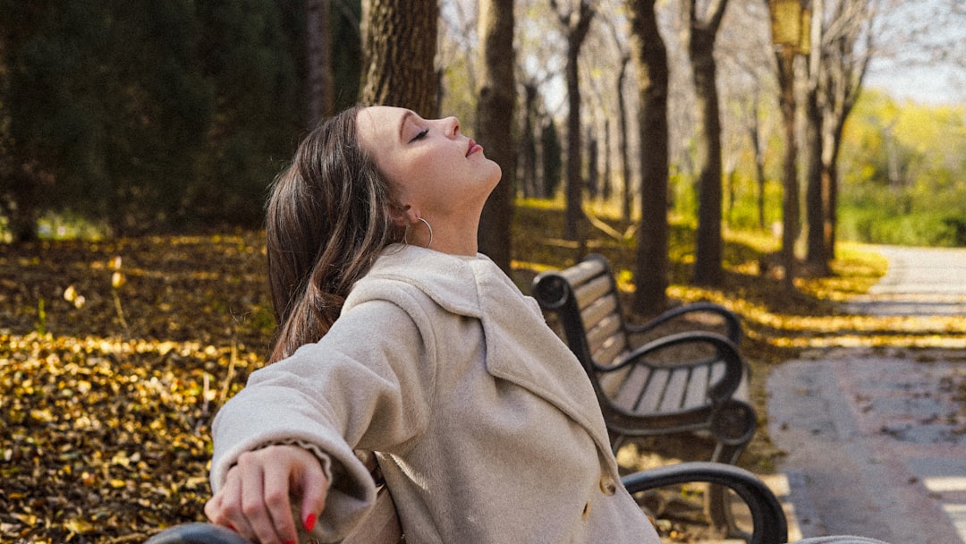 A woman walking through golden autumn leaves in a London park as part of her morning routine